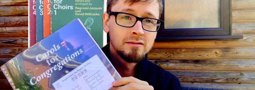 Ben Trigg holding a copy of Carols for Congregations